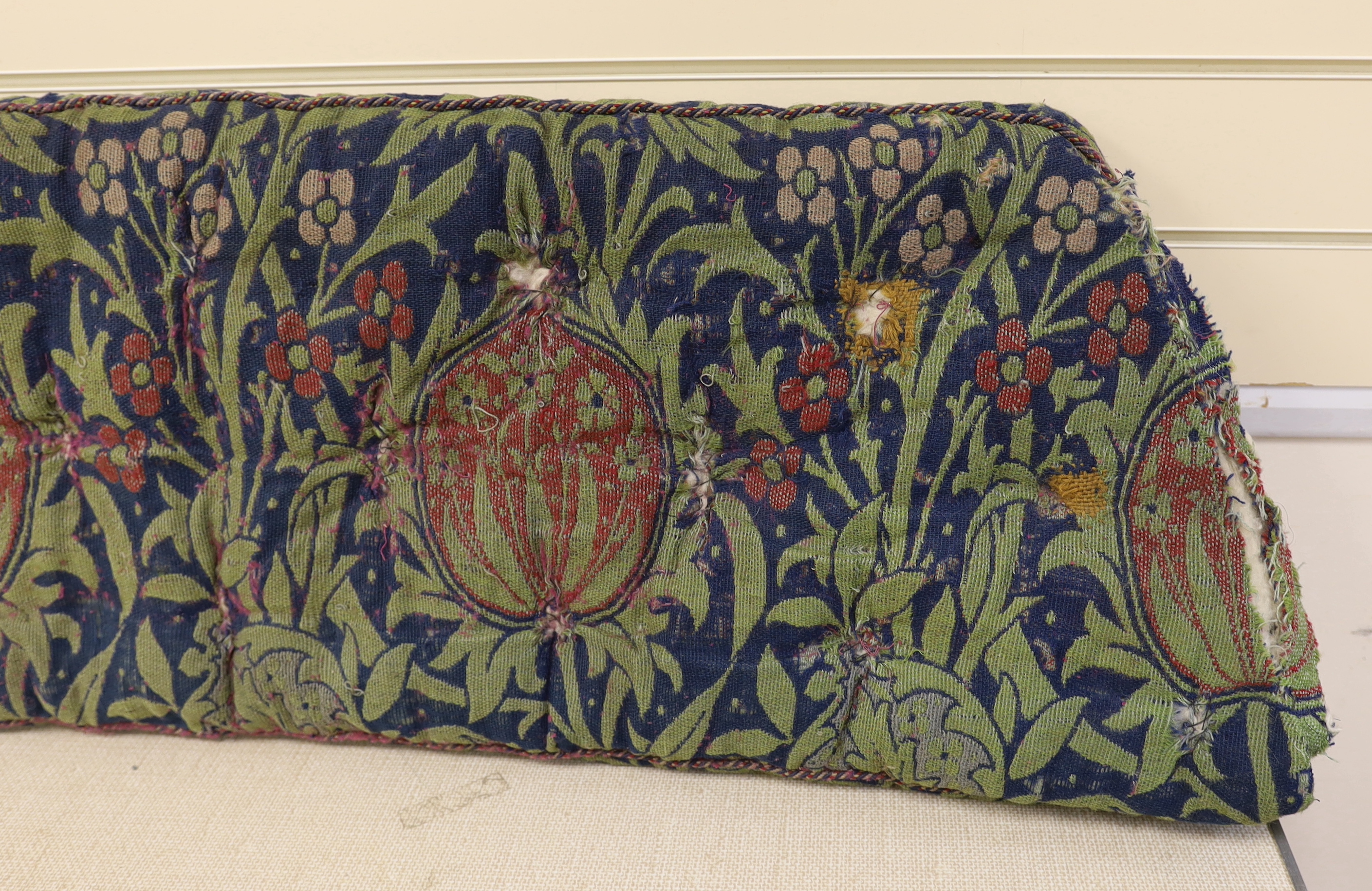 A William Morris Elmore, wool and mohair woven panel by J H Dearle circa 1900, used to cover a buttoned and braided window seat cushion, 196cm wide (at widest point) x 38cm deep 186 x 45cm